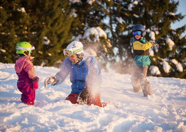 Vater mit Kinder spielen im Schnee und werfen Schneebälle.