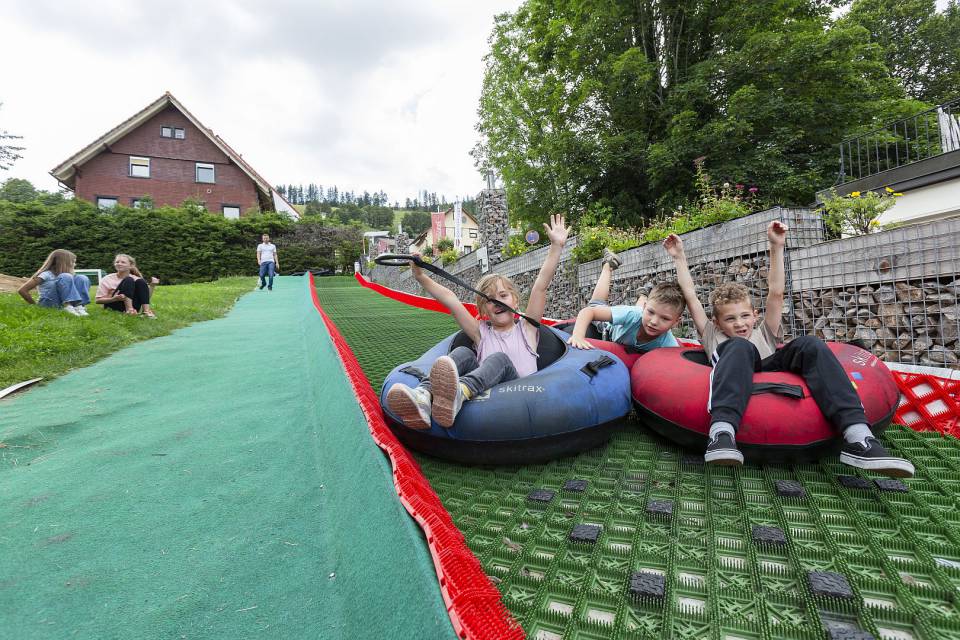 Drei kinder rutschen über Rampe mit Reifen