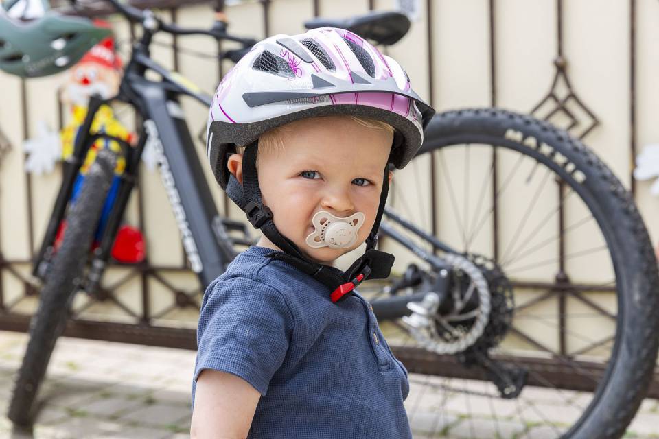 Kind mit Fahrradhelm steht vor einem Fahrrad.