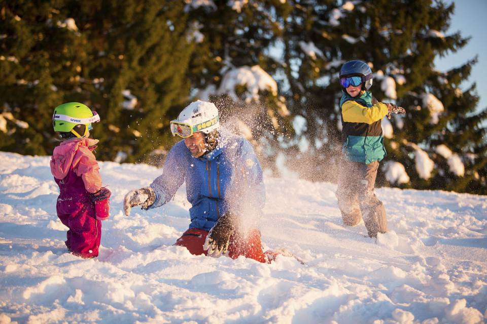 Vater mit Kinder spielen im Schnee und werfen Schneebälle.