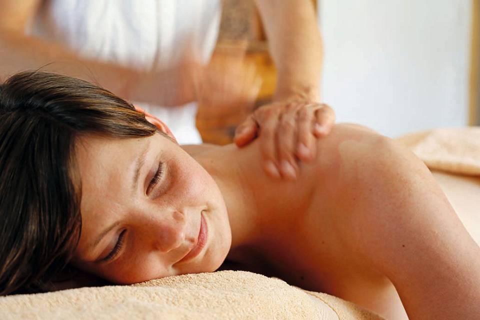 Frau erhält eine entspannende Rückenmassage in einem Wellnessbereich.