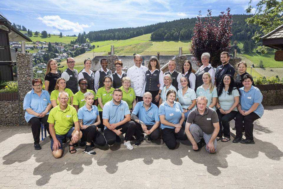 Gruppe von Hotelmitarbeitern posiert für ein Teamfoto im Freien.