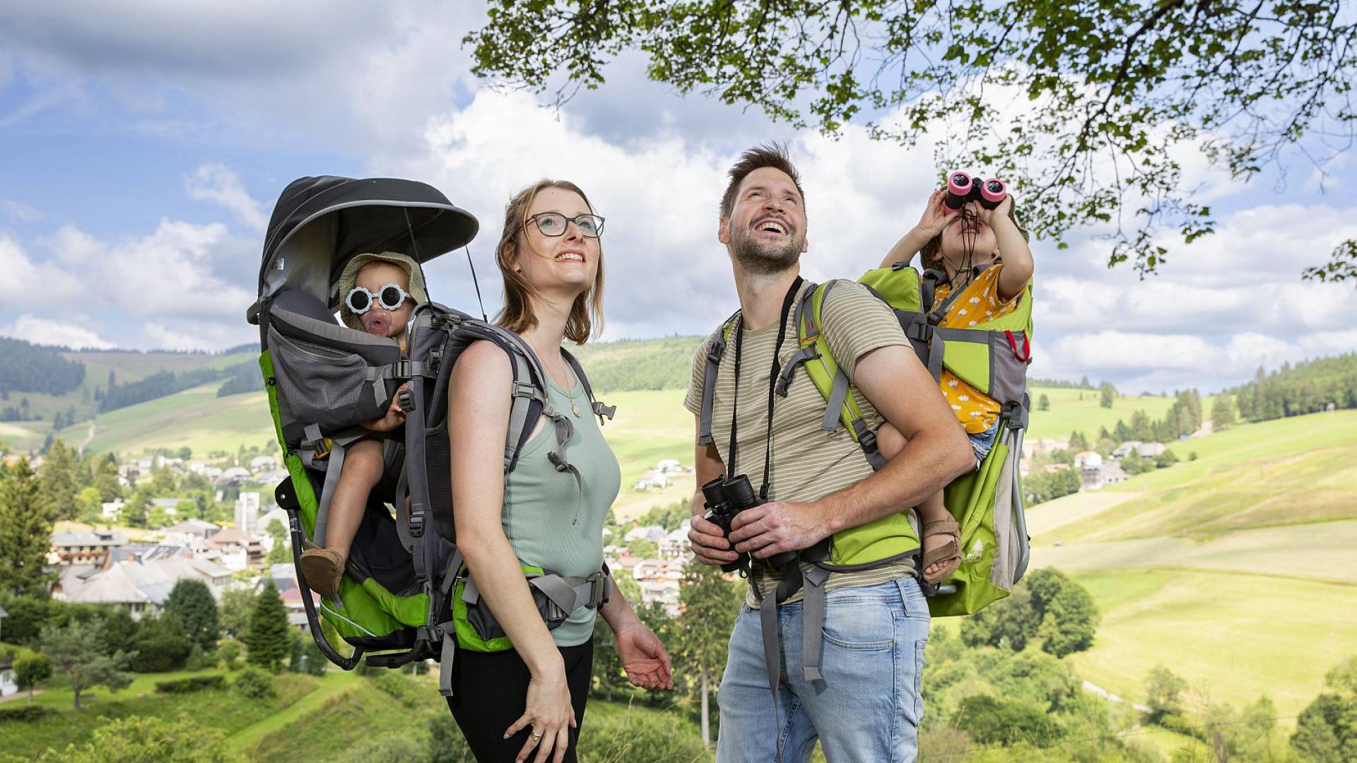 Familie mit Wanderkleidung und Kraxe posiert mit Panoramaausblick.