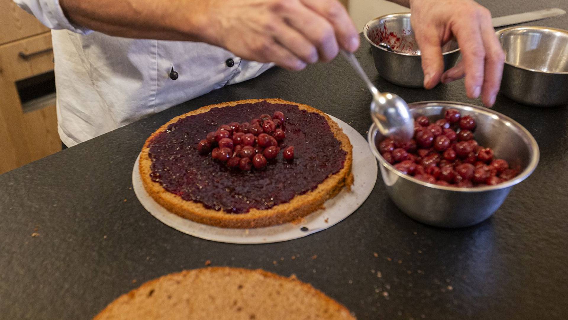 Nahaufnahme: Frische Kirschen werden auf einen Kuchenboden gelegt.