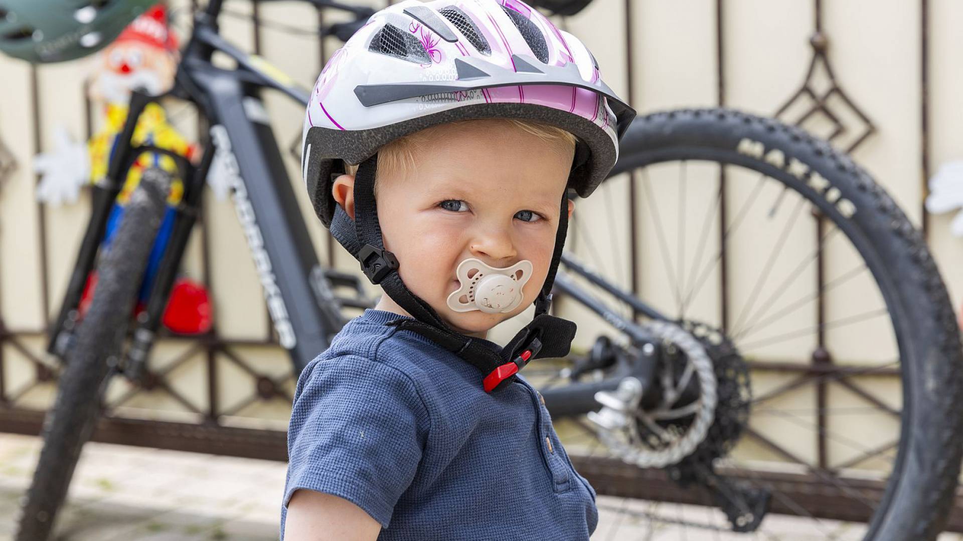 Kind mit Fahrradhelm steht vor einem Fahrrad.