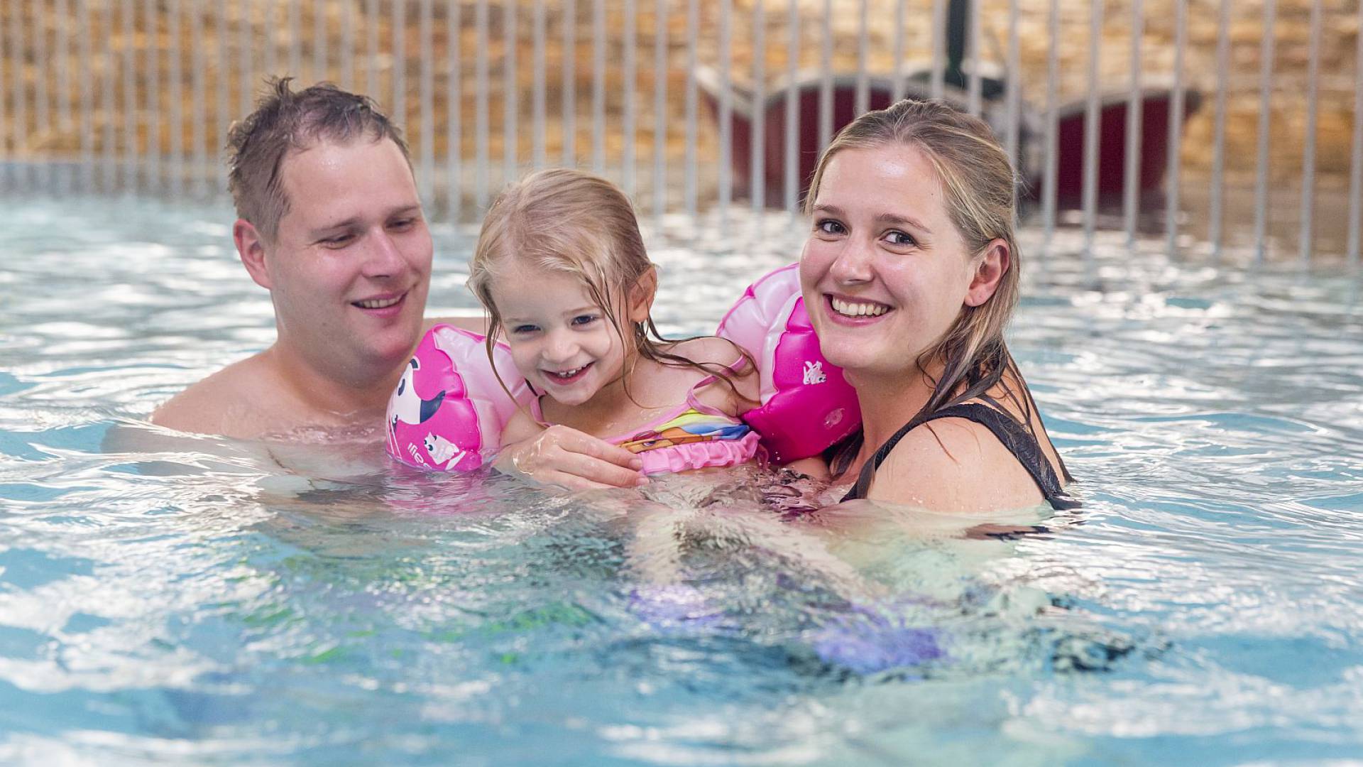 Familie mit Kind genießt das warme Wasser im Schwimmbad.