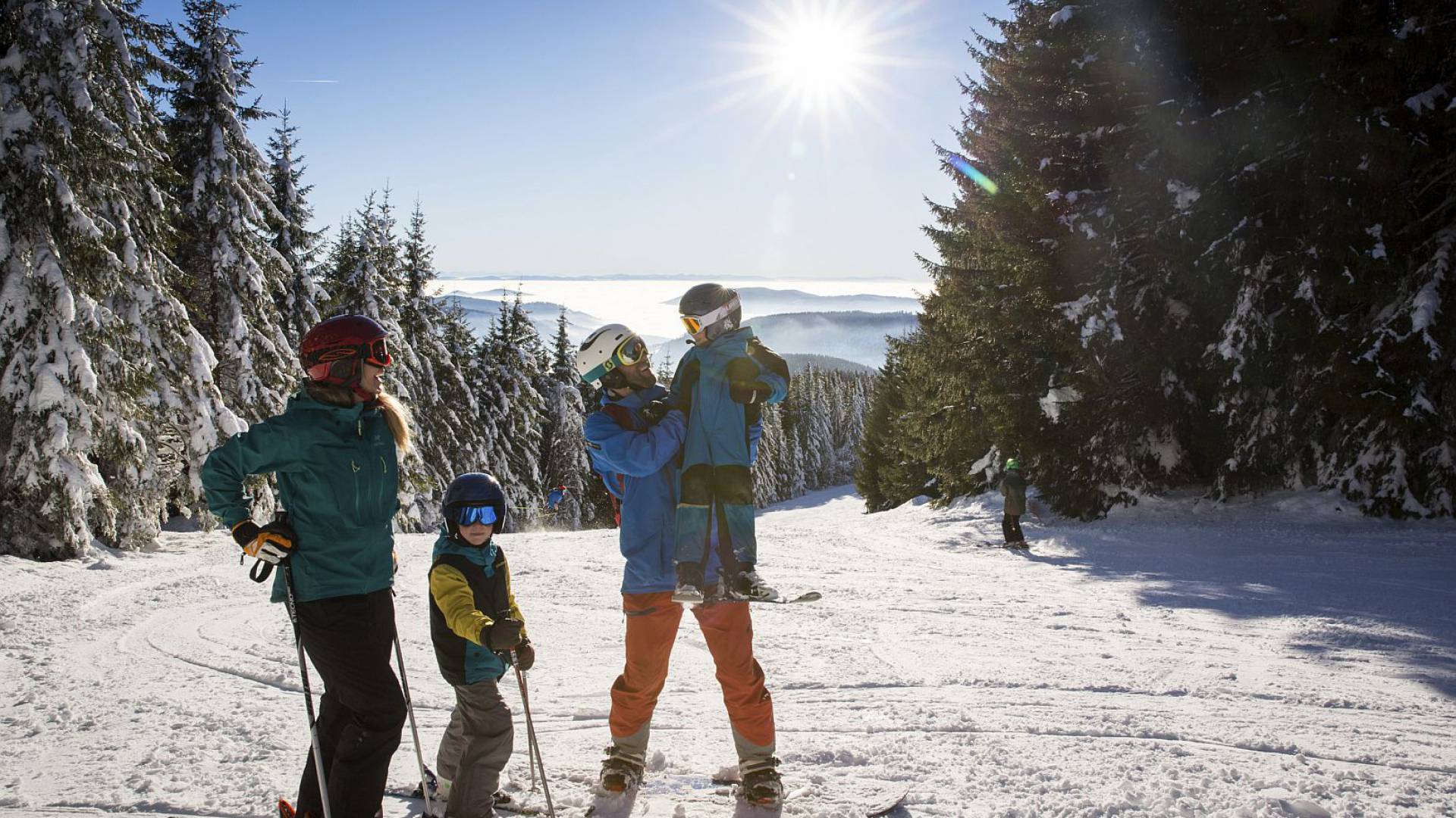 Familie fährt Ski durch eine sonnige Winterlandschaft.