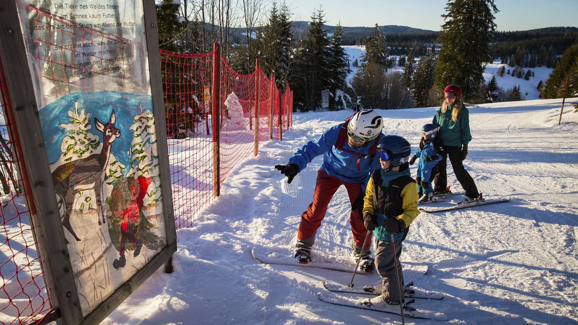 Familie auf Skiern im Schnee und begutachten ein Bild.