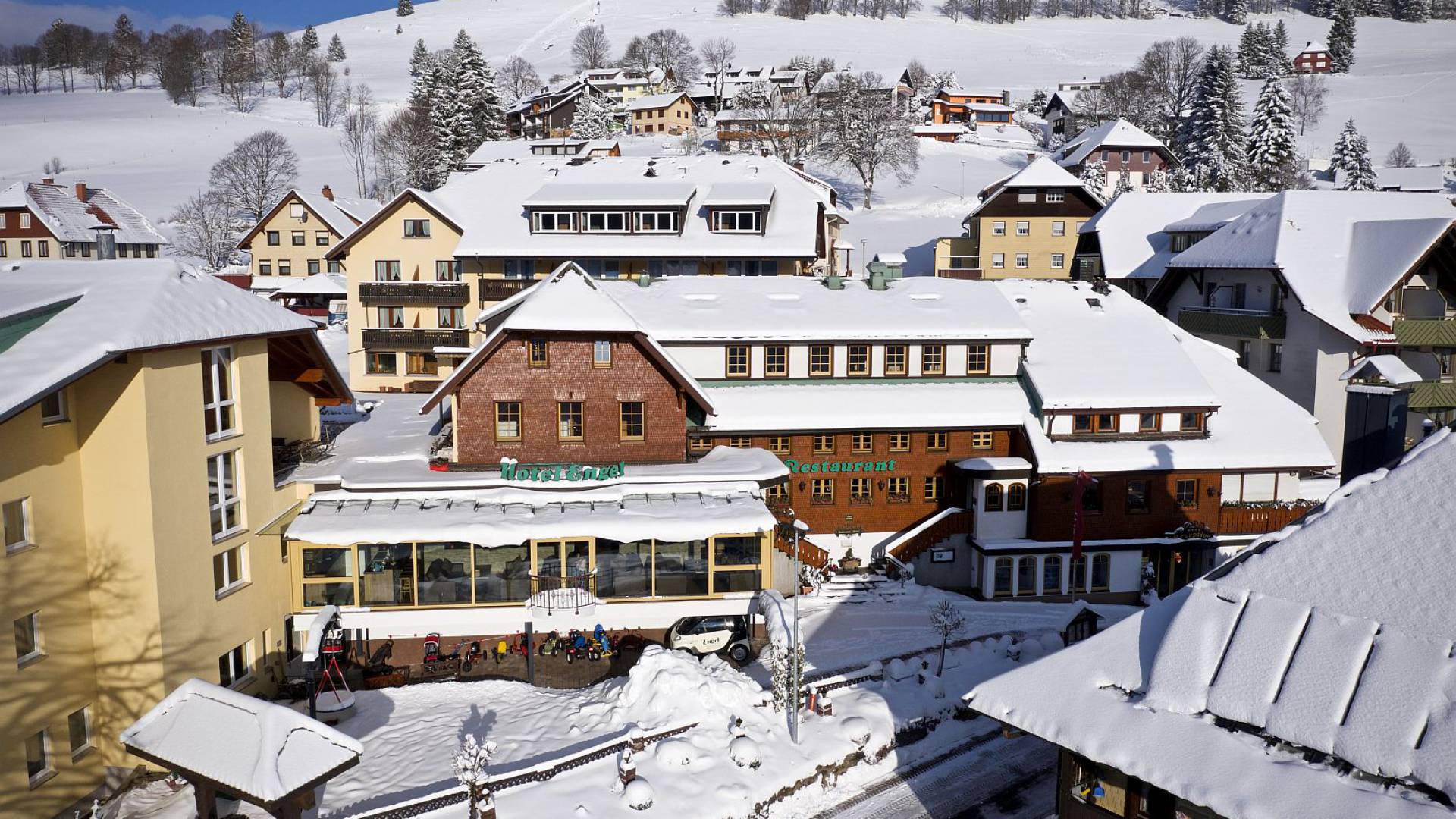 Verschneite Hotelanlage in einem idyllischen Bergdorf im Winter.
