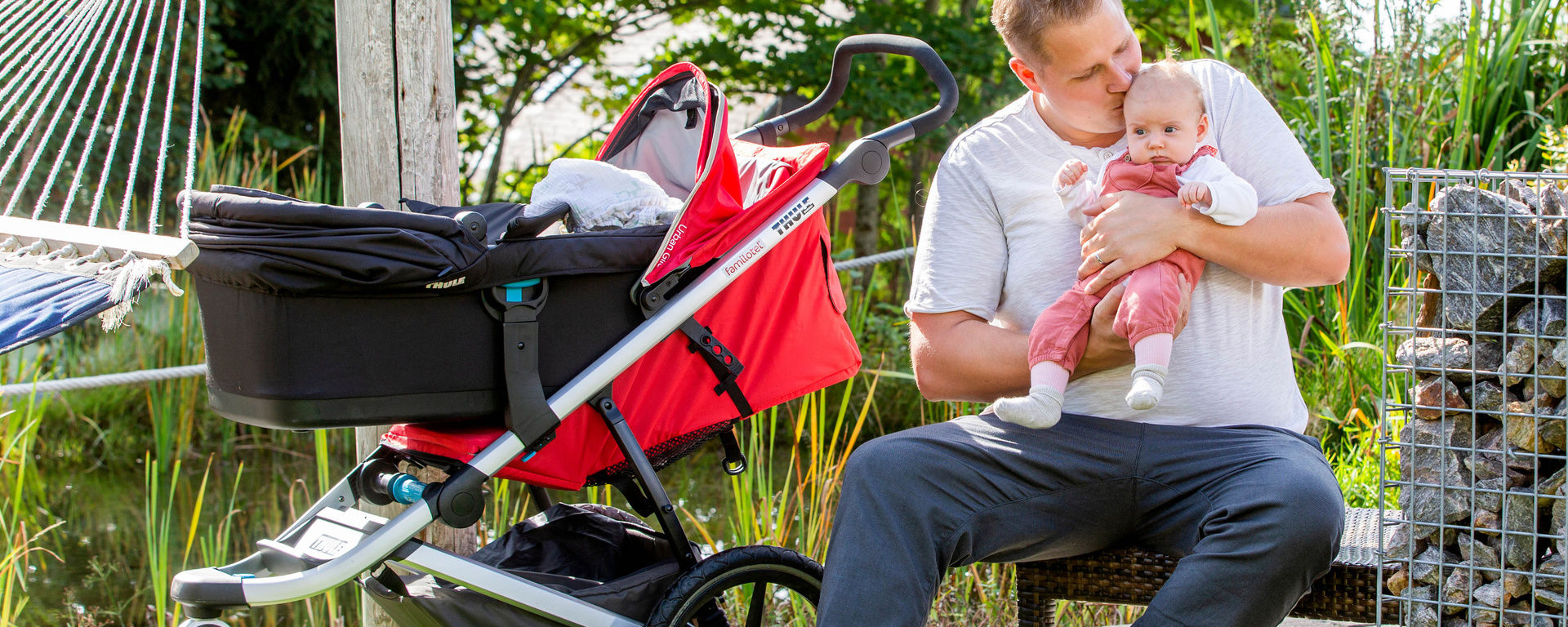 Vater sitzt auf Bank mit Kleinkind und Kinderwagen